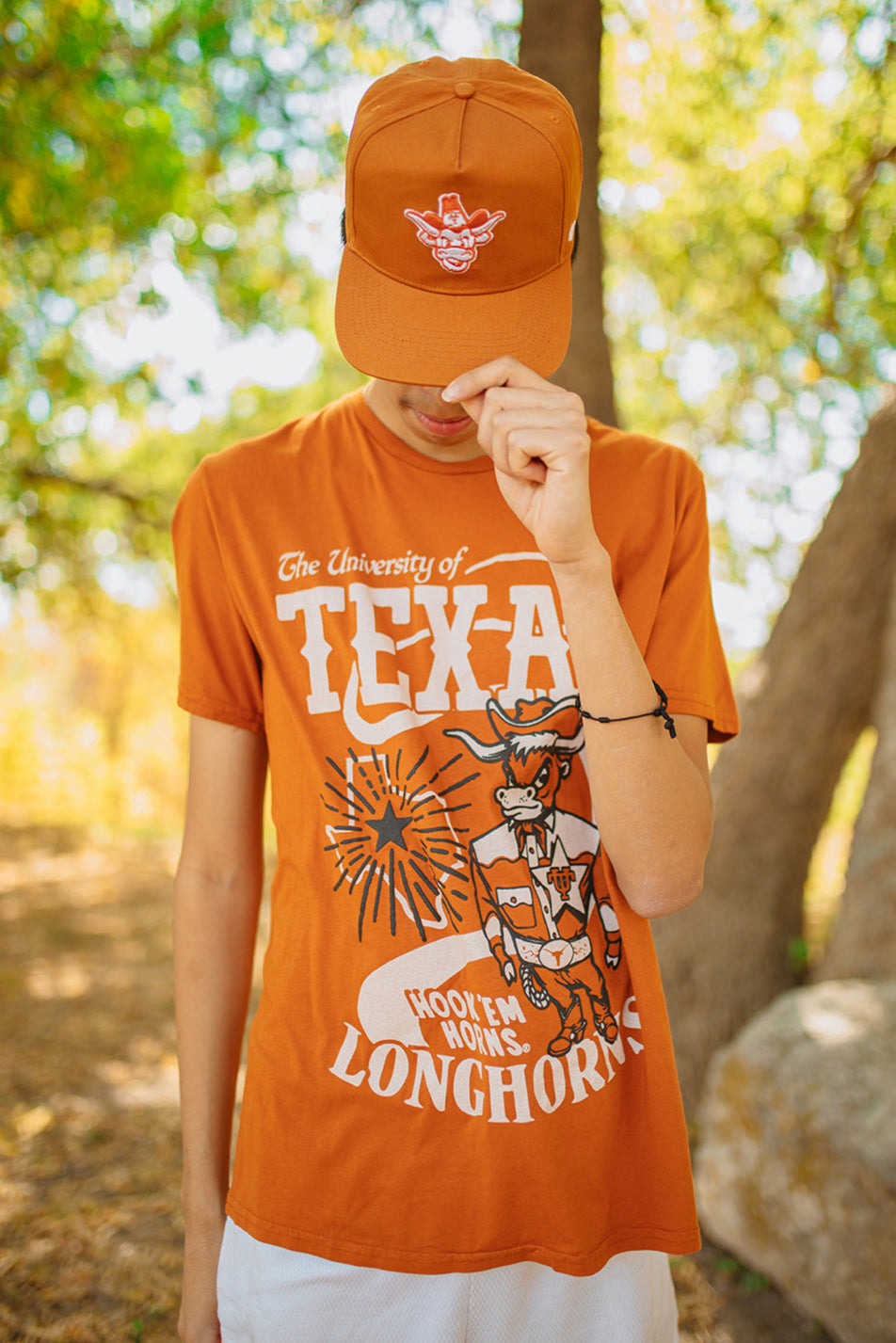 Person wearing an orange 'University of Texas Longhorns' t-shirt and cap outdoors.
