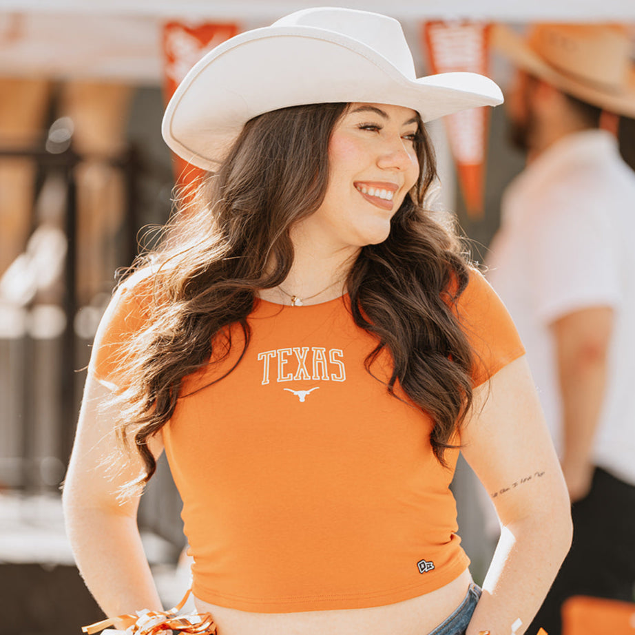 woman wearing burnt orange crop top with Texas longhorns graphic