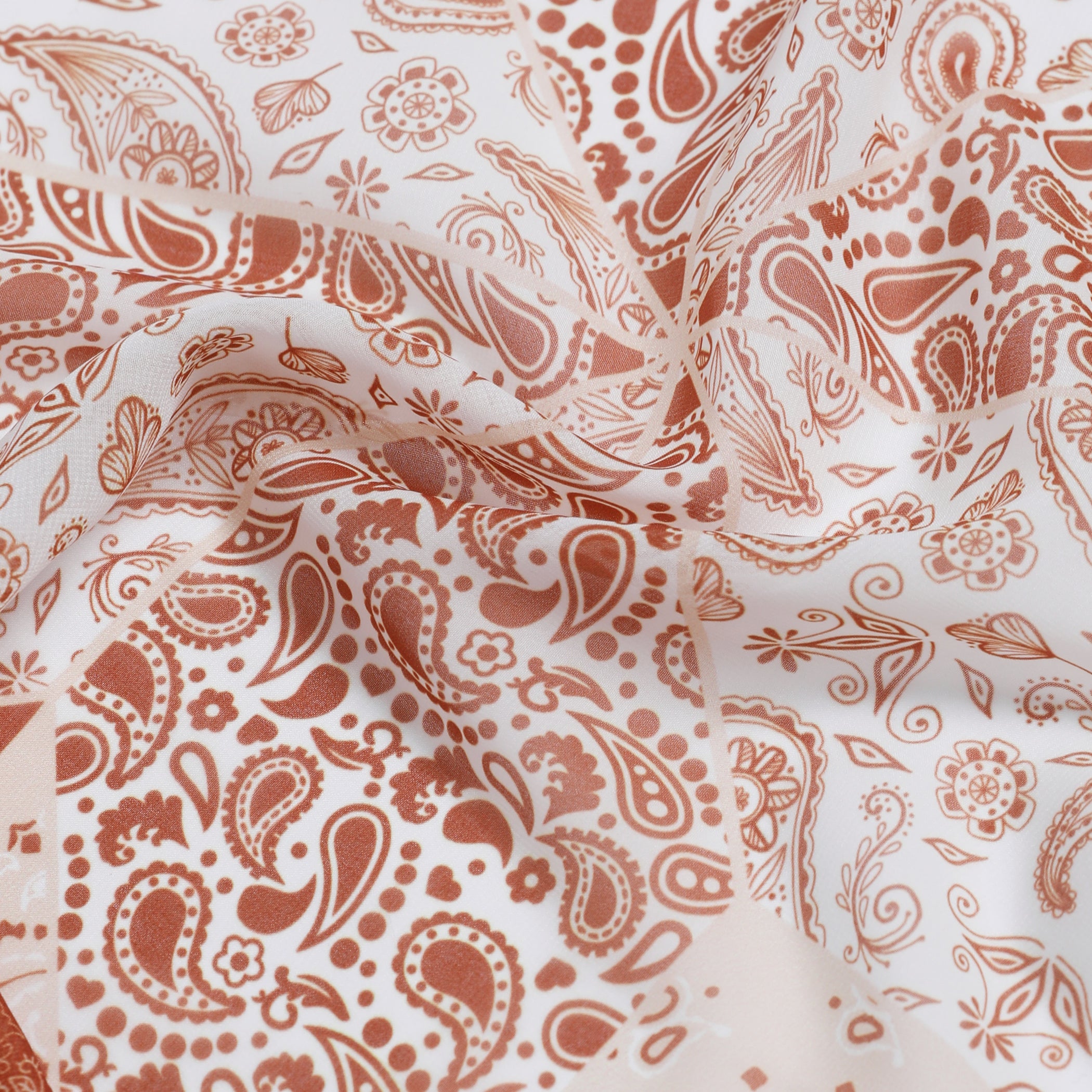 A close-up of a sheer white fabric with a warm rust-brown paisley and floral pattern, draped in soft folds.