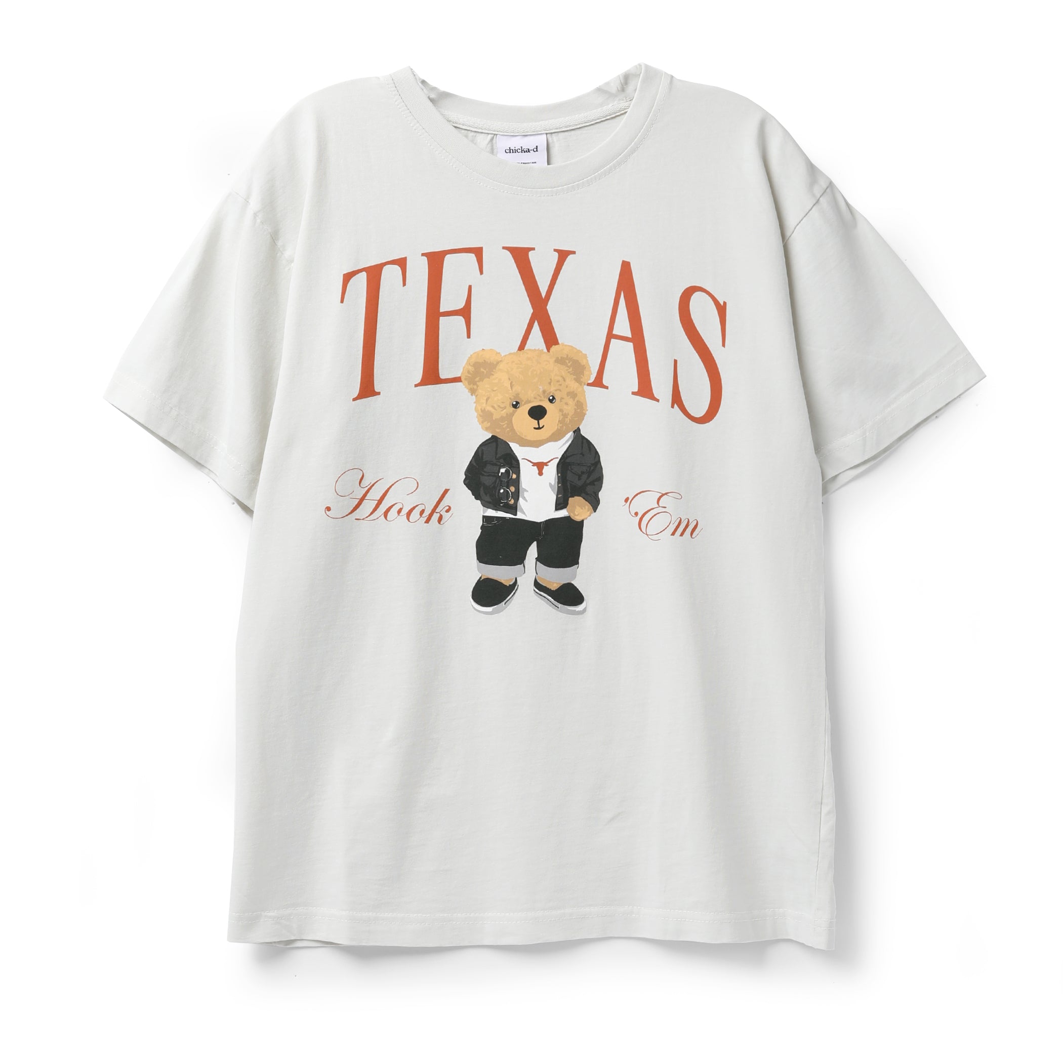 An oversized off-white t-shirt featuring a graphic print of a teddy bear in a black suit with a red tie, standing in front of the word 'TEXAS' in orange. The text 'Hook 'Em' is written in cursive below the bear.