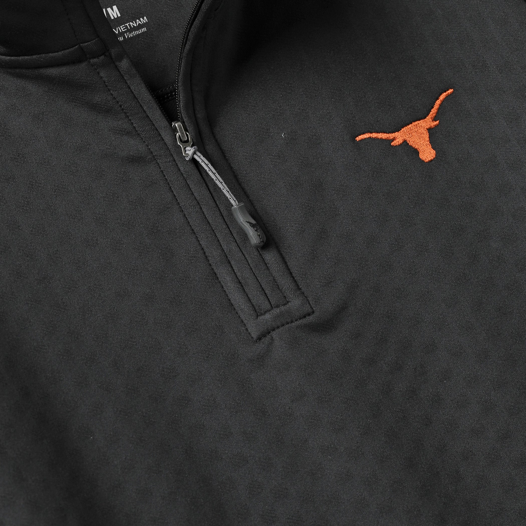 Close-up of a black quarter-zip pullover sweatshirt with a small orange embroidered Texas Longhorns logo on the chest.