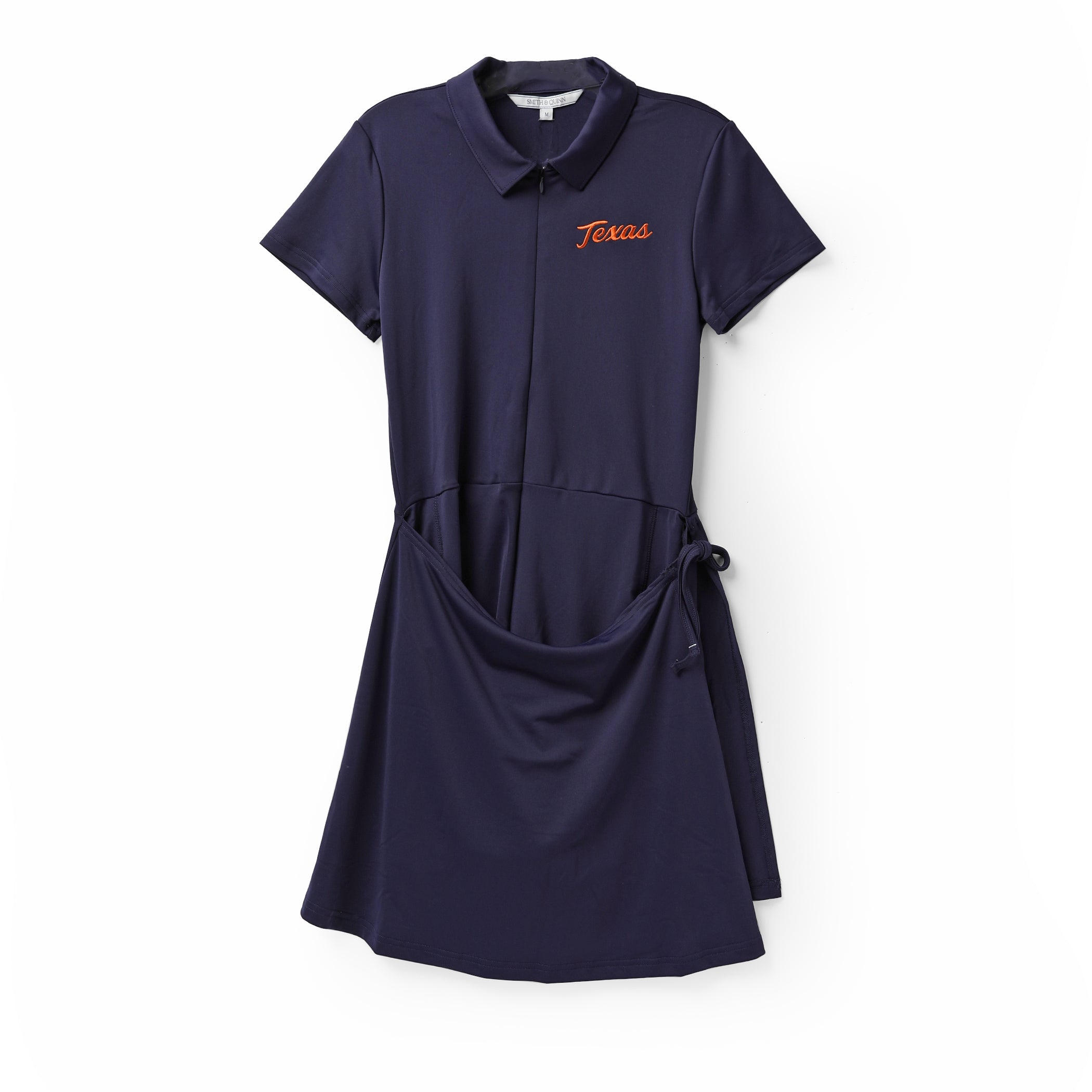 A navy blue short-sleeve polo dress with a collar, front button placket, and a side tie detail at the waist. The word 'Texas' is embroidered in orange on the left chest.