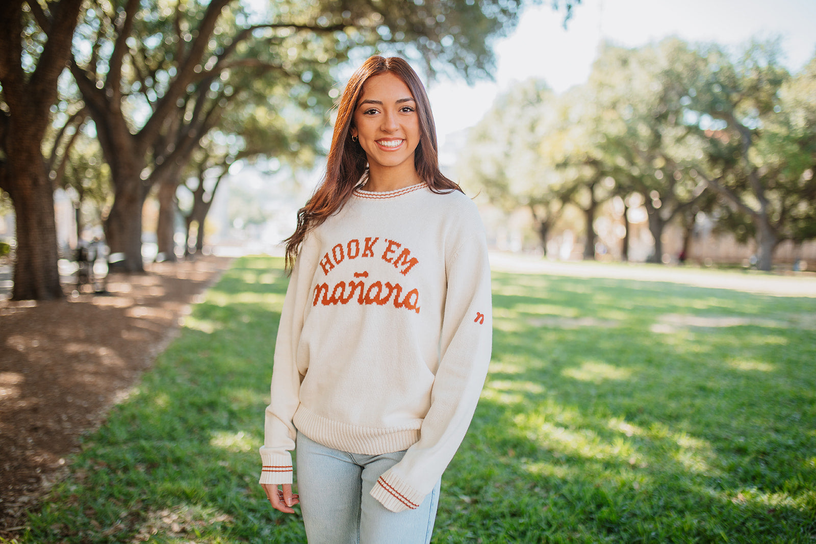 Woman wearing a 'Hook 'em' sweatshirt in a park setting. Texas Longhorns