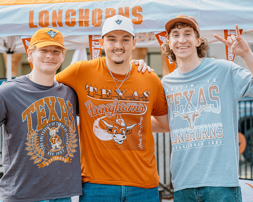 Three men posing together under a Texas Longhorns tent with 'Longhorns' printed on it.