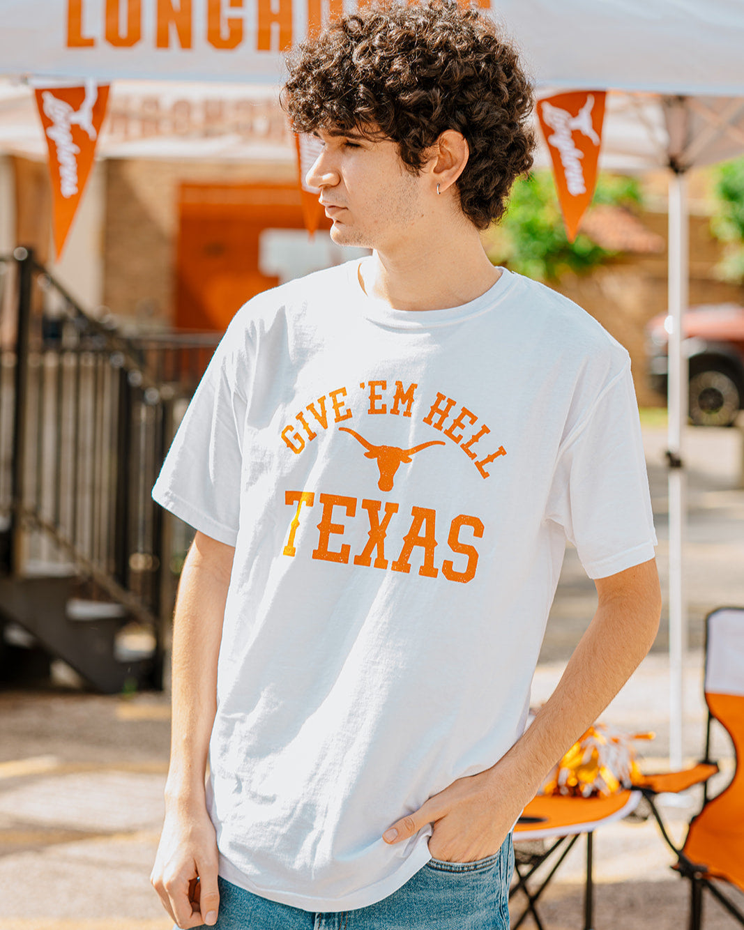 College student wearing a University of Texas tshirt that says Give 'Em Hell Texas with a burnt orange steerhead