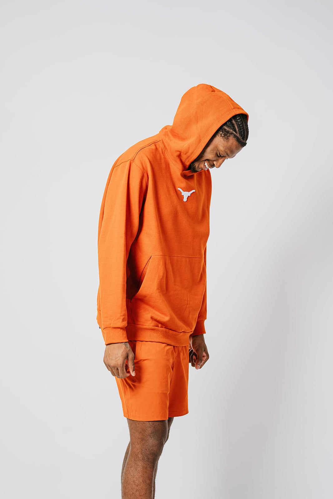 Texas longhorns basketball player. wearing an orange hoodie and shorts set on a white background. Texas Longhorns merch
