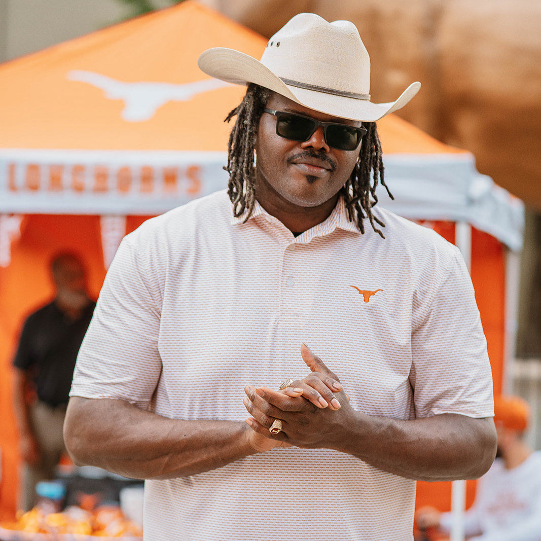 Man wearing white and burnt orange Texas Longhorns polo at a college football tailgate