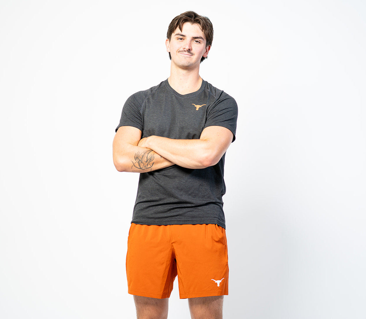 Person wearing a dark gray t-shirt and orange shorts with a logo on a white background. Texas Longhorns merch