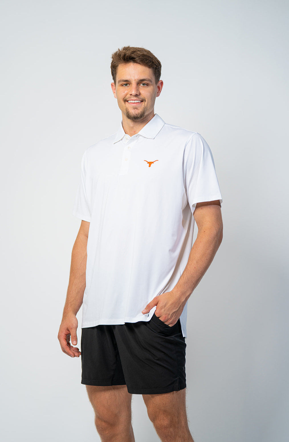 Texas Longhorns basketball player.  wearing a white polo shirt with a logo and black shorts on a light gray background. Texas Longhorns merch