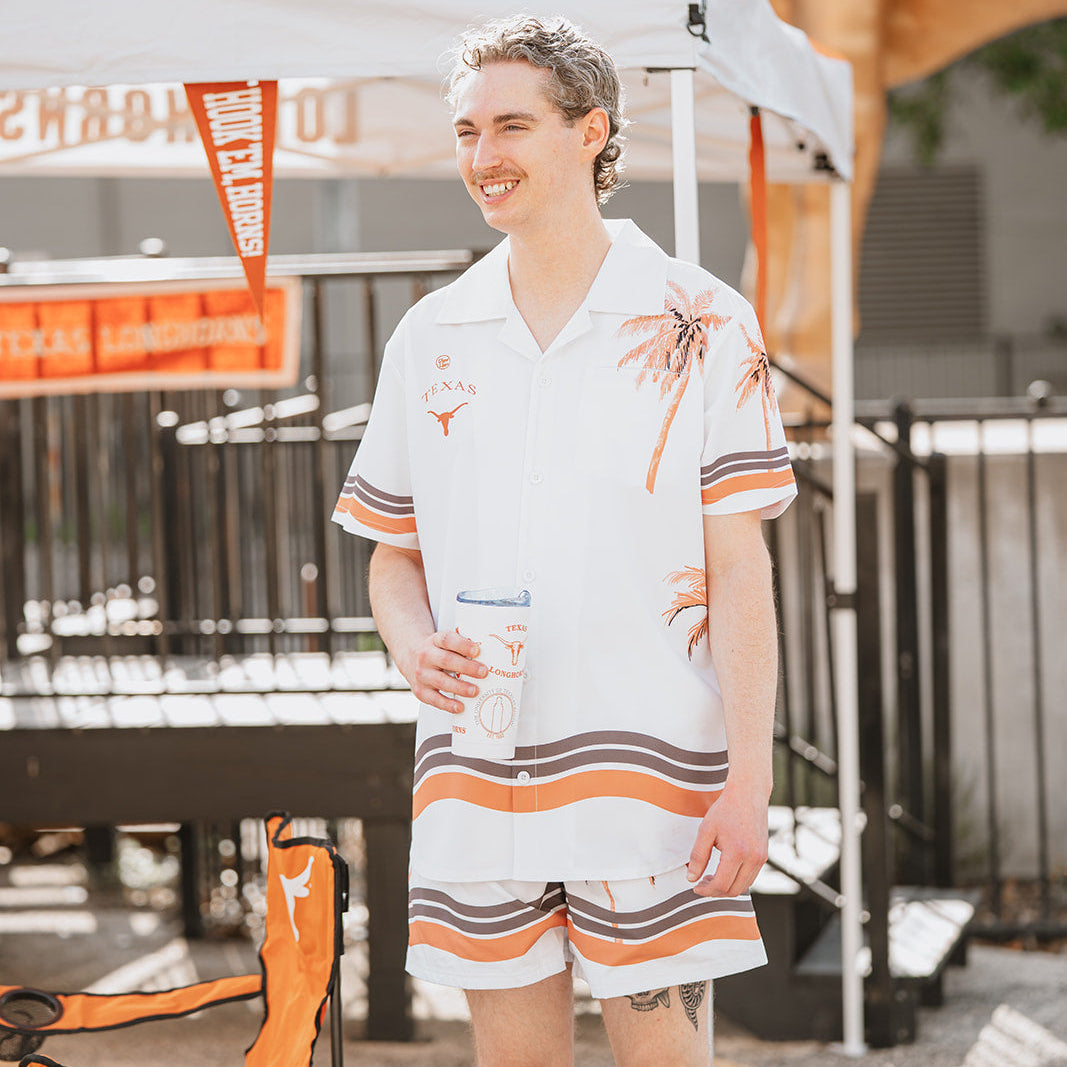 Man wearing matching shirt and shorts with palm and Longhorn print in burnt orange and white