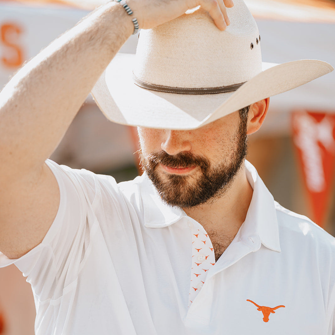 Man wearing cowboy hat and white Texas longhorn polo