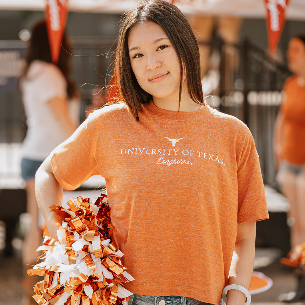 woman wearing burnt orange heathered crop tee that says University of Texas Longhorns