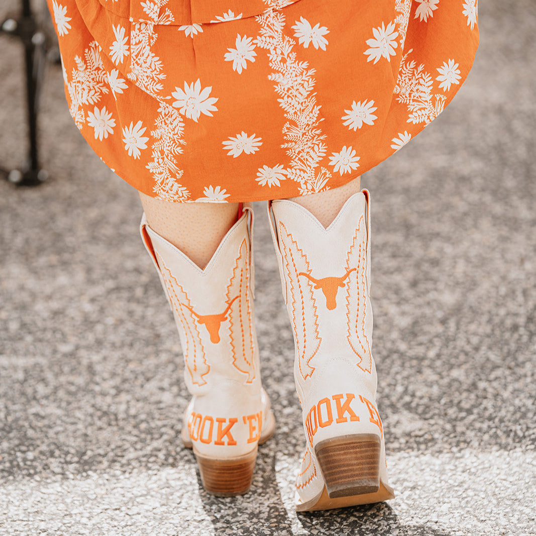 white cowboy boots with burnt orange stitched detailing that says hook 'em horns