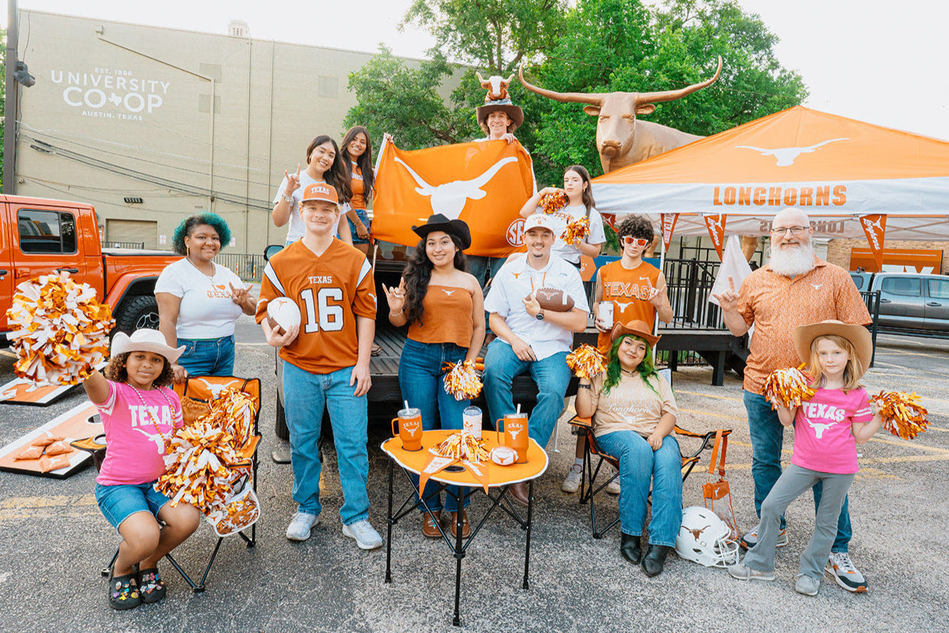 Group of people at a Texas Longhorns event with burnt orange attire, including a large banner and a truck.