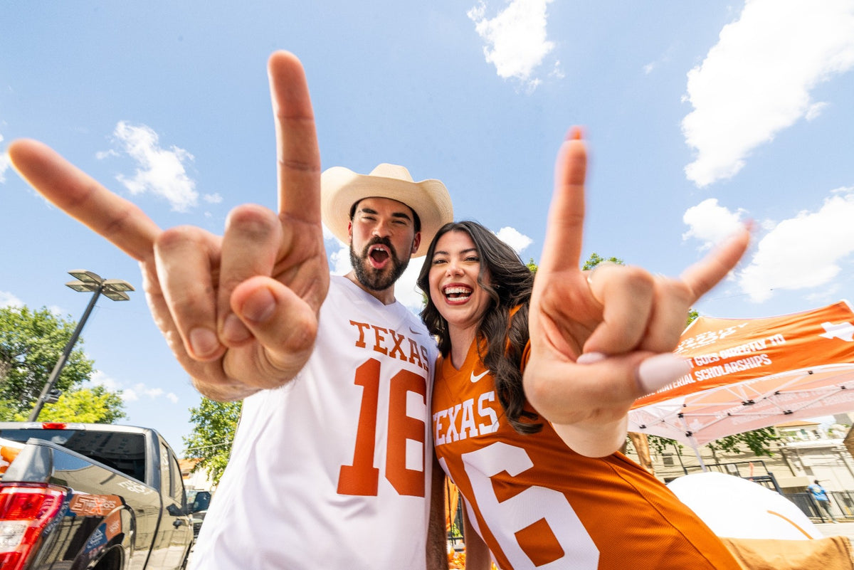Longhorn fans giving the hook em sign in longhorn jerseys at a tailgate