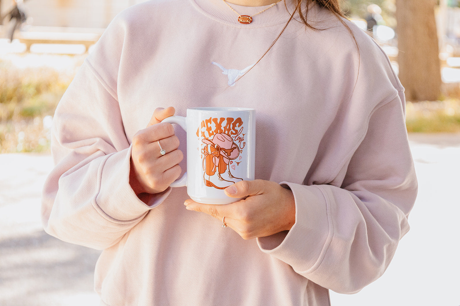 Person holding a mug with a design outdoors