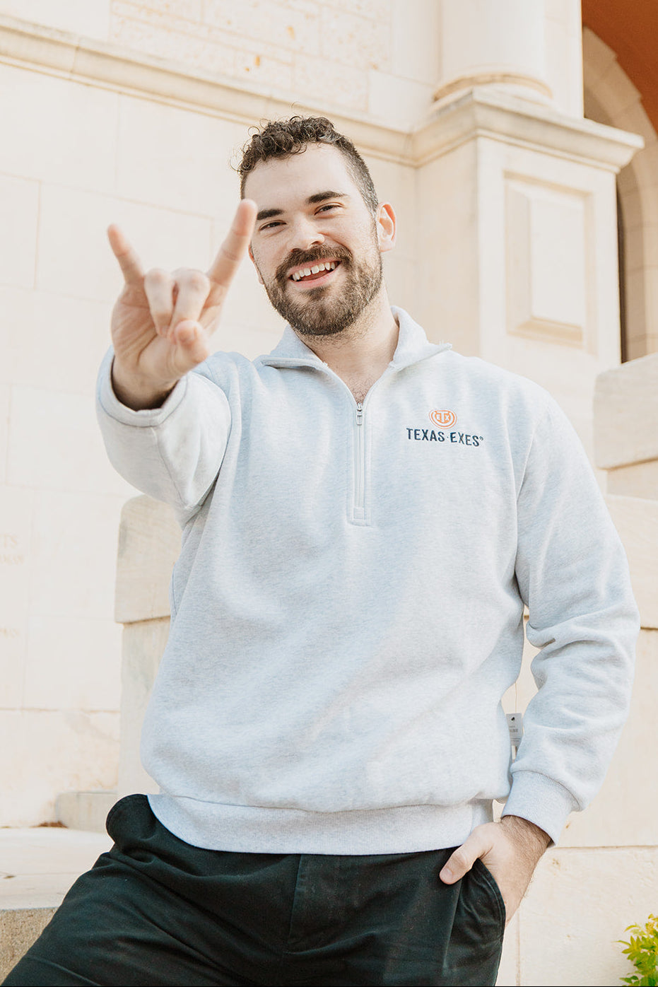 Man wearing a light gray sweatshirt with 'Texas Tech' logo, sitting outdoors.