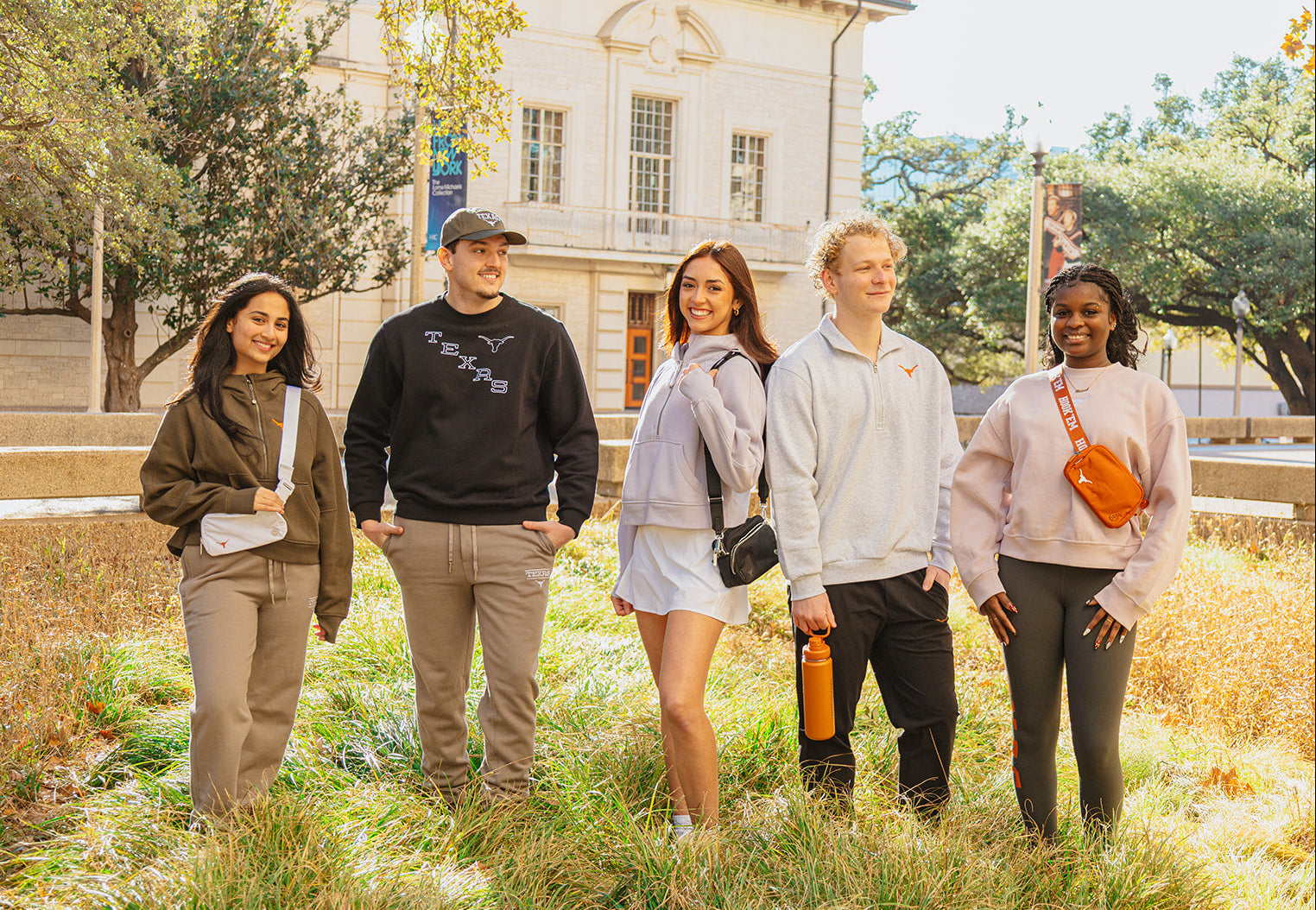 Five students standing outdoors on the campus wearing longhorn merch