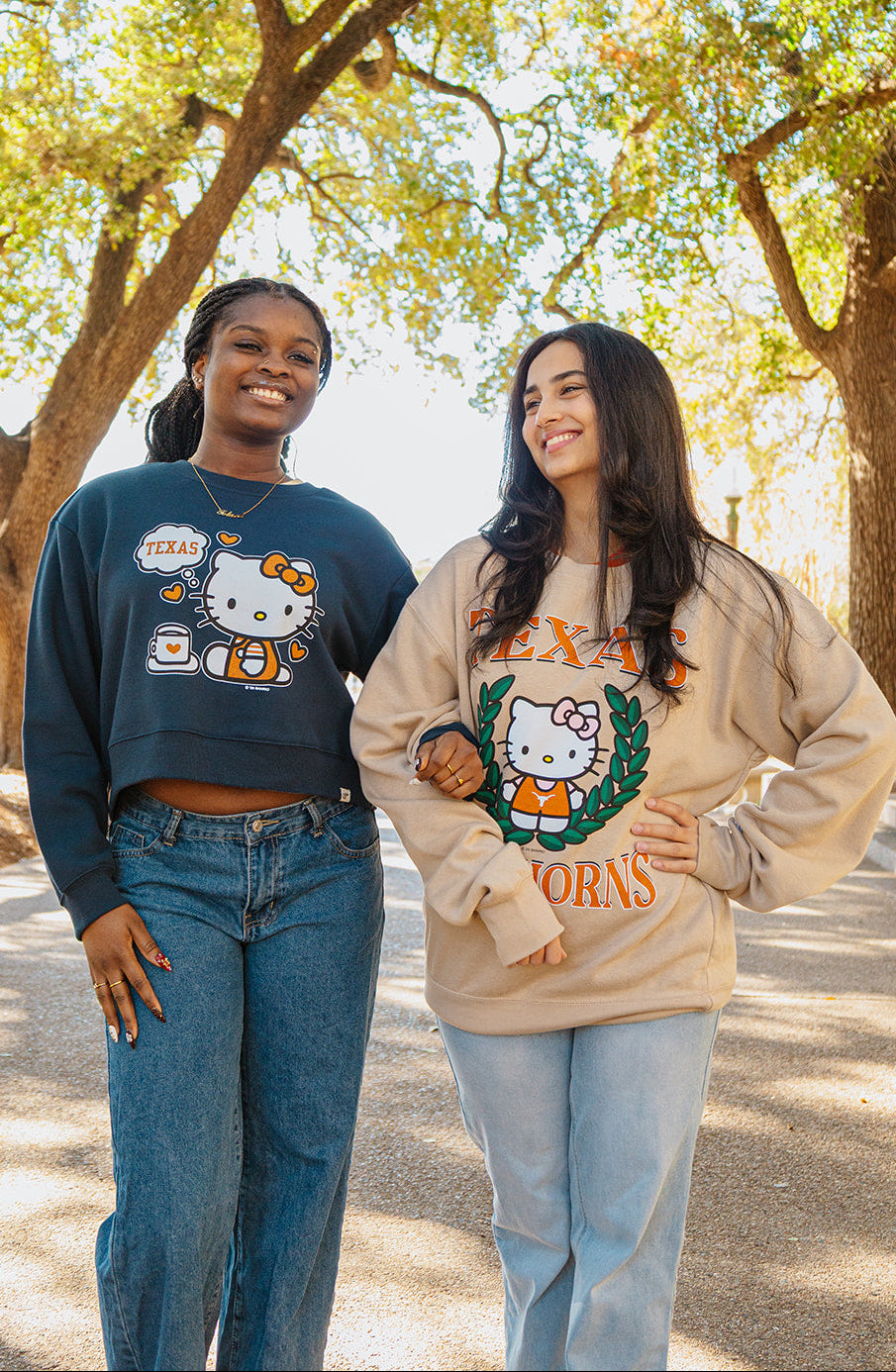 Two women wearing Hello Kitty-themed sweatshirts standing outdoors with trees in the background.