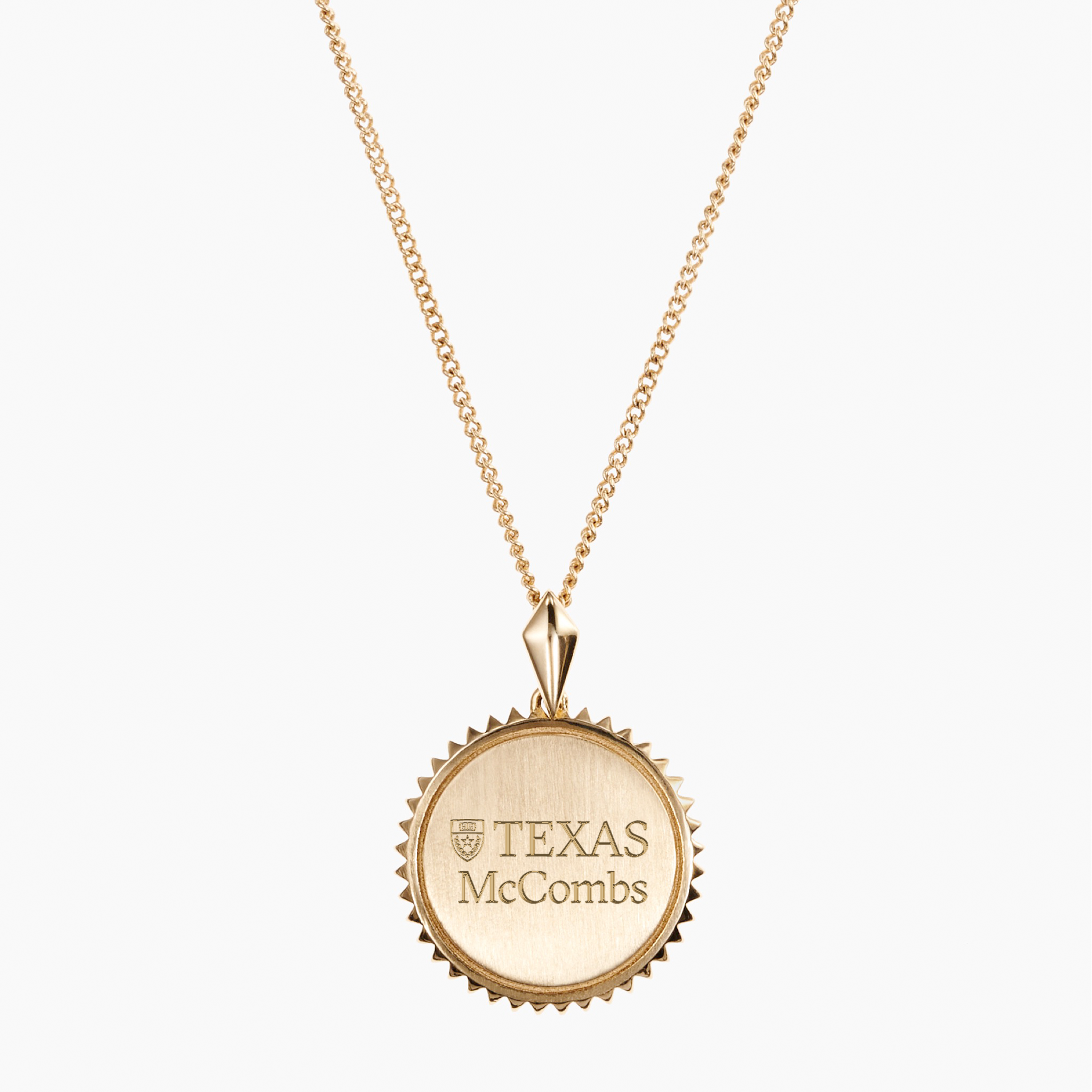 A gold chain necklace with a round, scalloped-edge pendant engraved with the Texas McCombs logo, shown against a light gray background.