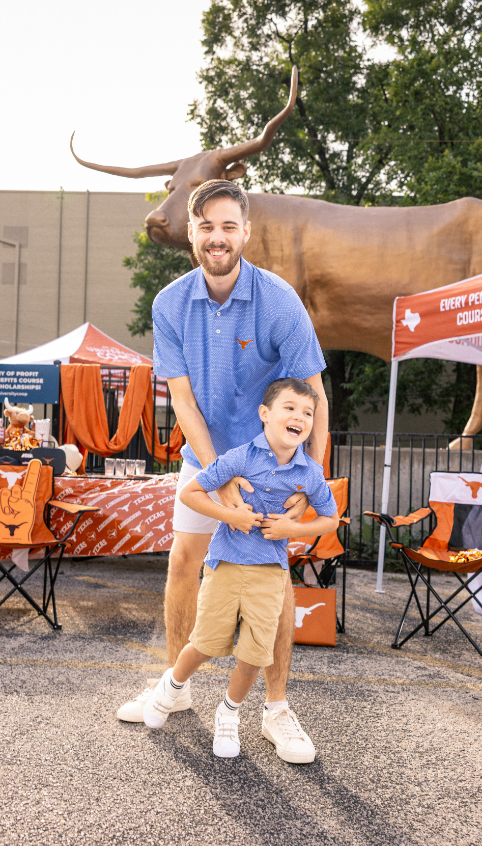 Longhorn dad and son celebrating at a tailgate. Wearing matching longhorn polos. 