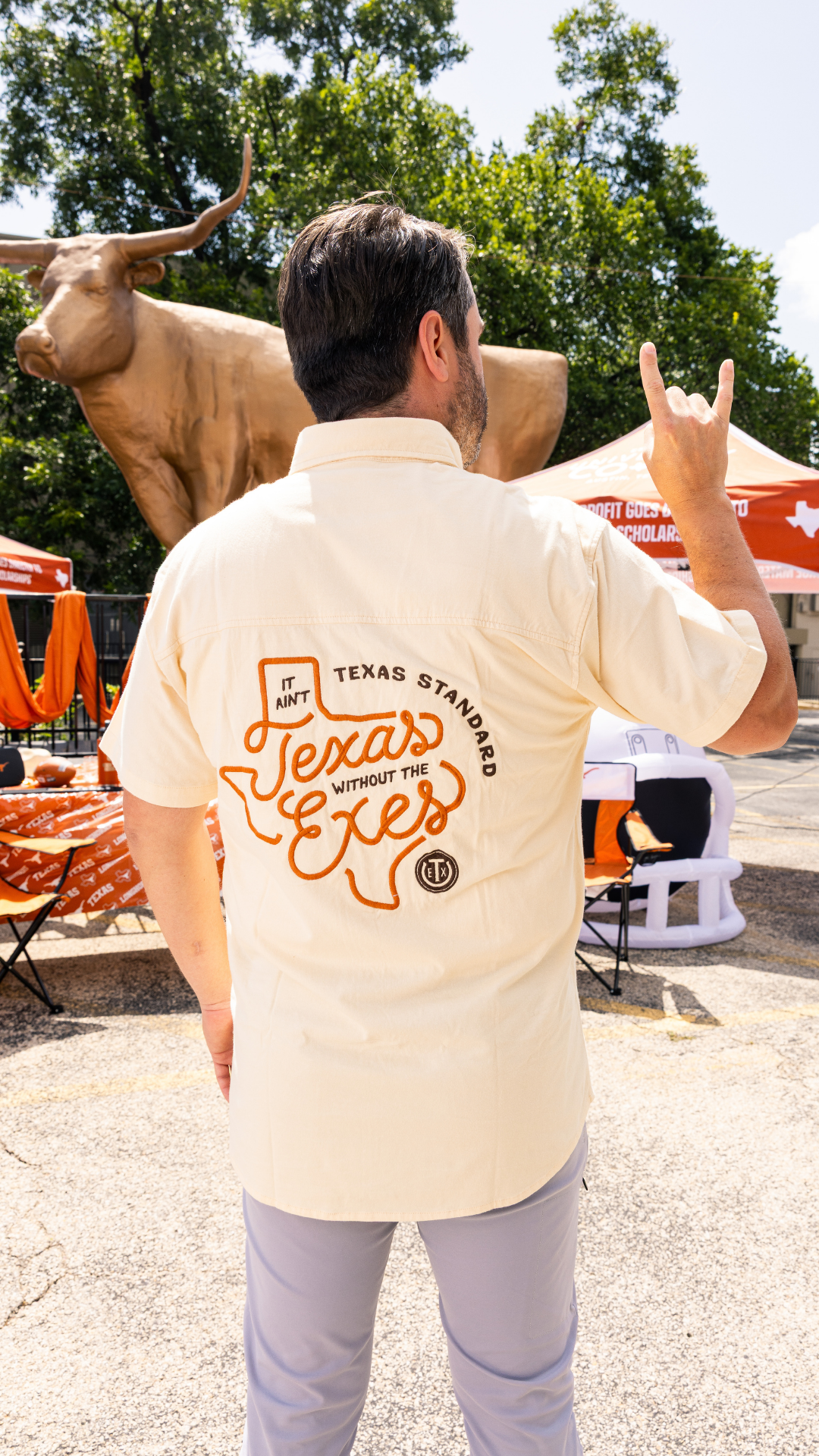 Texas Exe giving the hook em horns showing off a texas exe shirt